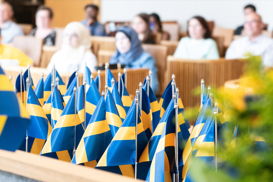 Svenska bordsflaggor står ihop med människor i bakgrunden