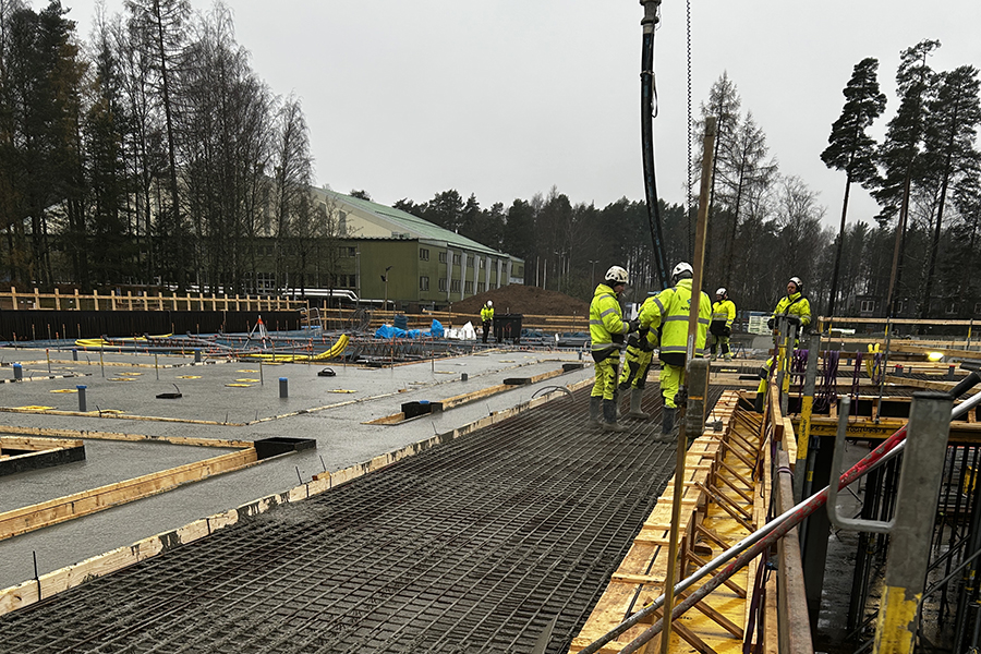 En byggarbetsplats. Till höger står en grupp människor i varselkläder.