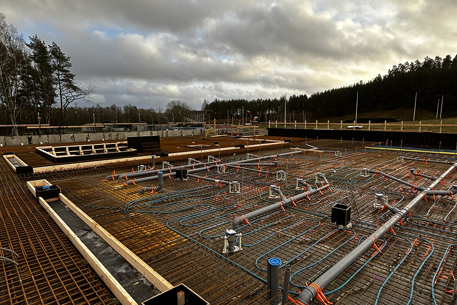 En byggarbetsplats där man ser en betonggrund med nät i metall ovanpå. 