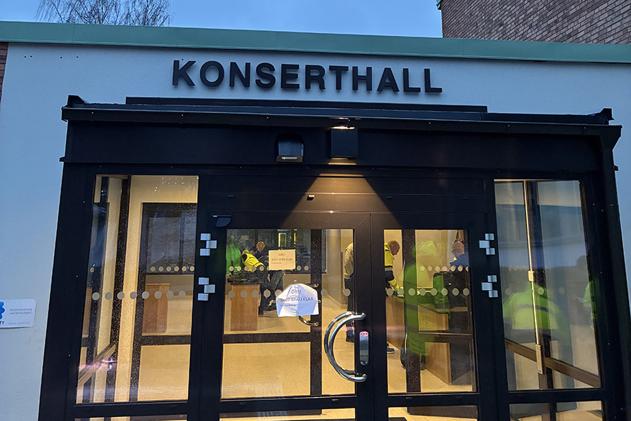 Glasdörrar på en byggnad. Ovanför dörrarna står det konserthall med versaler.