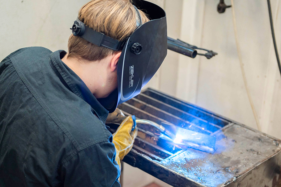 Elev svetsar med full skyddsutrustning. 