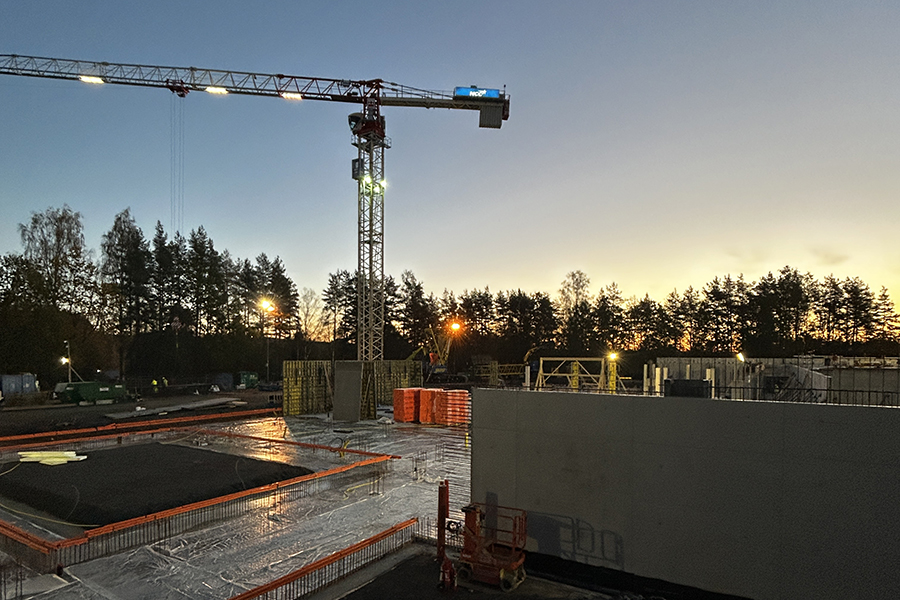 En byggarbetsplats i kvällsljus. En kran syns i bakgrunden.