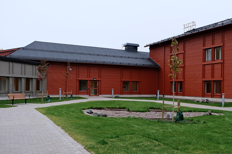 En innergård med gräsmatta. Byggnadens fasad är röd.