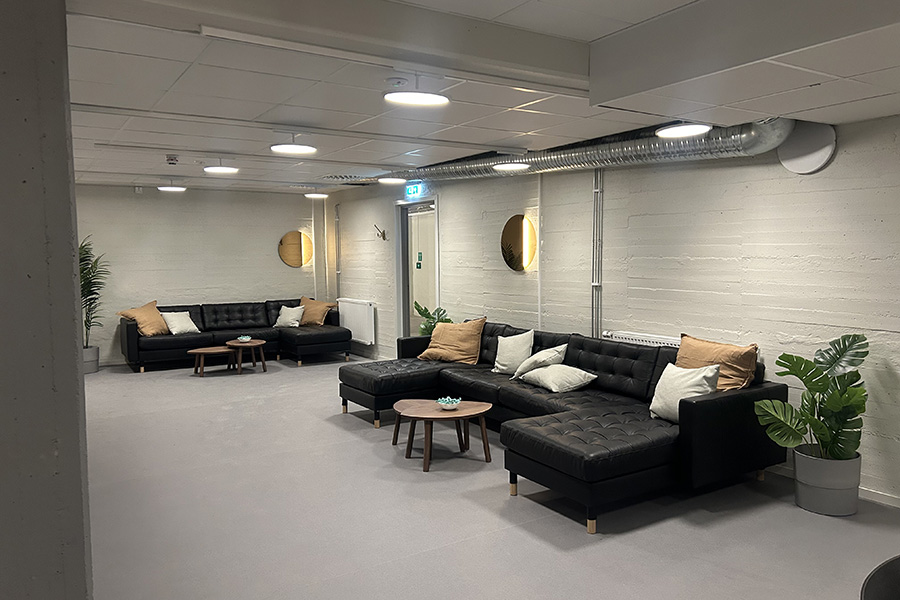 Ett rum med vita väggar och en svart soffa längst ena väggen. 