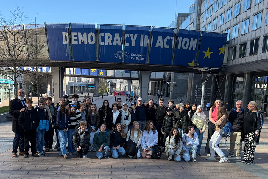 En grupp elever som står framför europaparlamentet i byssel.