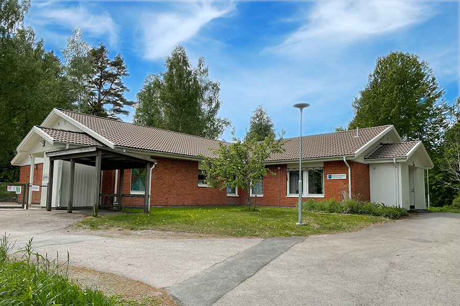 Blåklintens förskola. Röd tegelbyggnad med träd och grönyta runt omkring.