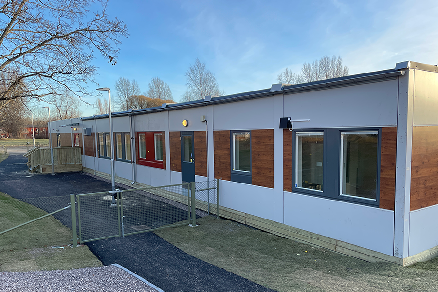 Gullvivans förskola. Röd enplansbyggnad med svart tak och en innergård med asfalt. 