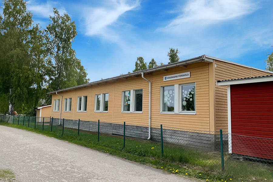 Häsängens förskola. En gul enplansbyggnad med grönt staket mellan byggnaden och cykelbanan som ligger precis bredvid.  