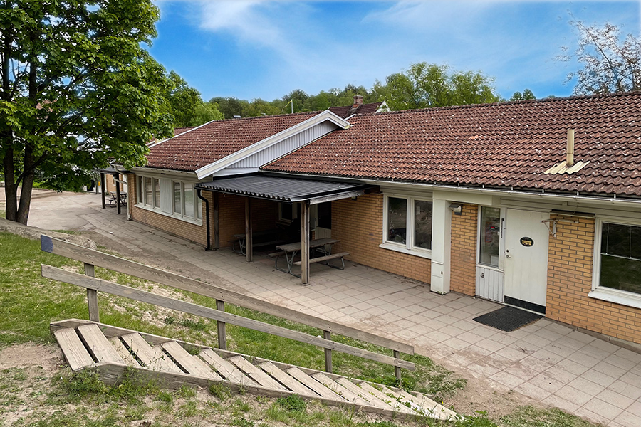 Kompassens förskola. Förskolan ligger nedanför en gräskulle med en trätrappa. Byggnaden är en enplansbyggnad med gult tegel. 