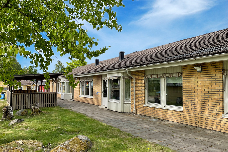 Ängens förskola. En gul tegelbyggnad med vita detaljer kring dörrar och fönster och svarta tegelpannor. Stenplattor längs med byggnaden. 