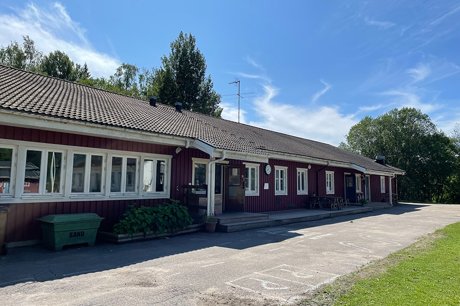 Lonnhyttan/Granbergsdals förskola. En röd träbyggnad med vita knutar och asfalt längs byggnaden som är målad med vitkrita. 