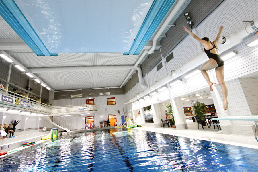 En tjej som hoppar simhopp från en trampolin i ett badhus.