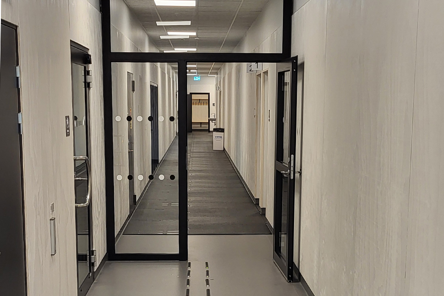 En lång korridor med glasdörrar med svarta karmar halvvägs.