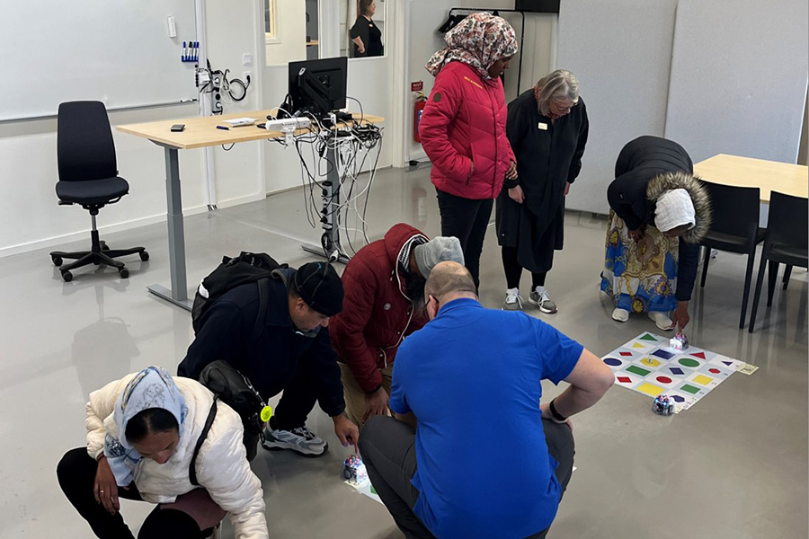 Elever sitter tillsammans på golvet och testar att programmera minirobotar 