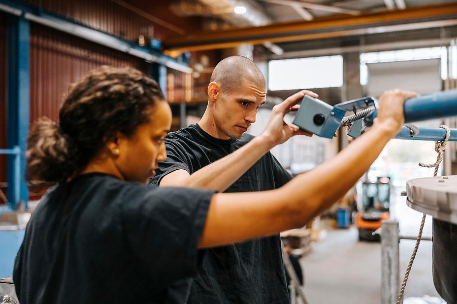 Tjej och kille diskuterar arbete i en industri