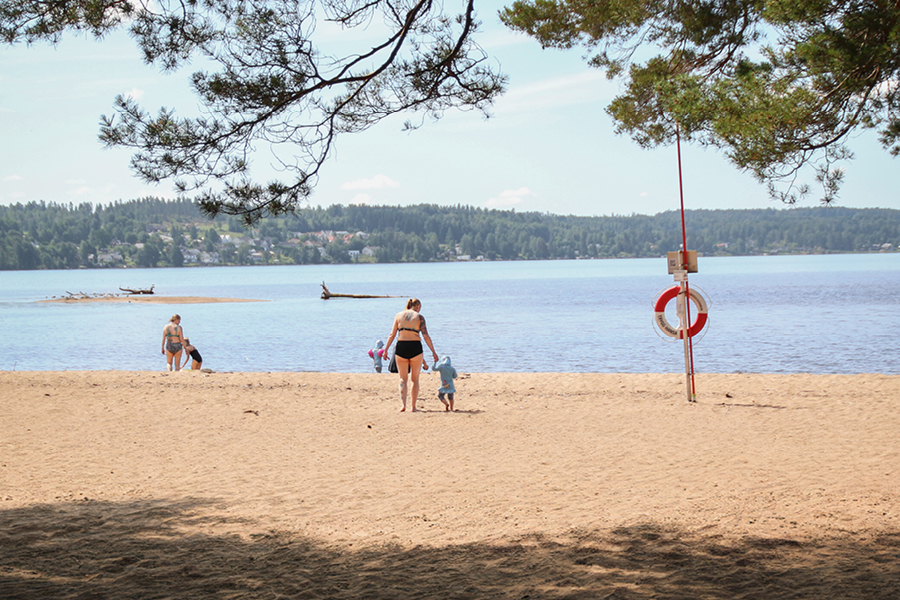 Bild på Sandviksbadets strand och några badgäster.