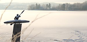 Ett tennisrack i närbild. Framför ligger en tennnisboll. 