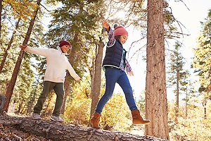 Höstklädda barn som leker i skogen