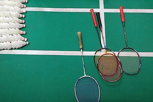 Badmintonracketar och fjäderbollar ligger på ett grönt golv