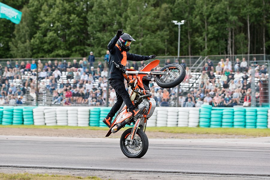 Kille gör trix på motorcykel med massa publik i bakgrunden