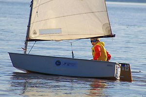 Ett barn som sitter i en segelbåt och seglar.